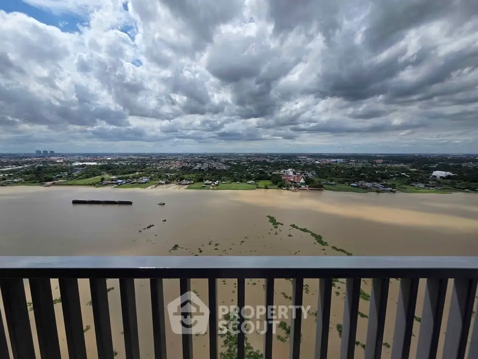 Stunning panoramic view from high-rise balcony overlooking expansive river and cityscape under dramatic skies.