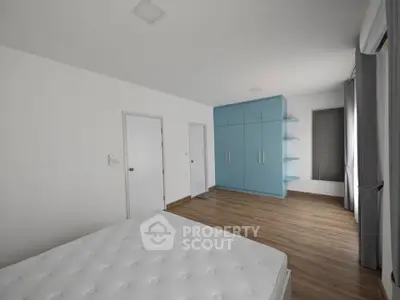 Spacious bedroom with modern blue wardrobe and wooden flooring