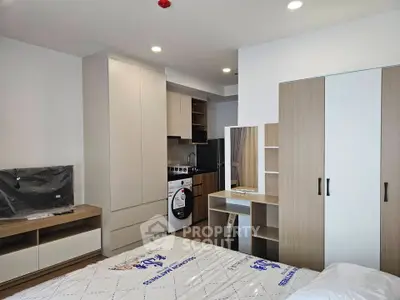 Modern studio apartment with sleek furniture and integrated kitchen appliances.