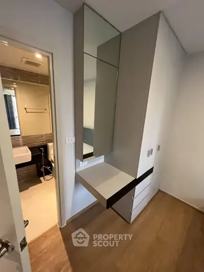 Modern apartment interior with sleek built-in wardrobe and view into stylish bathroom.