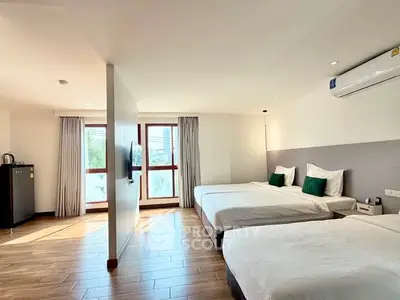 Spacious modern bedroom with twin beds, large windows, and natural light.