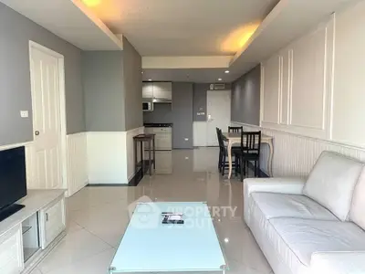 Spacious modern living room with open kitchen and dining area, featuring sleek furniture and elegant design.
