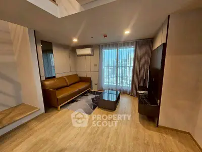 Modern living room with city view, featuring sleek furniture and natural light.