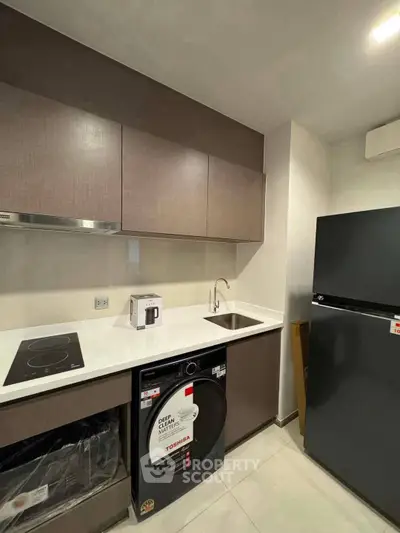 Modern kitchen with sleek cabinetry, induction cooktop, and integrated appliances in a compact layout.