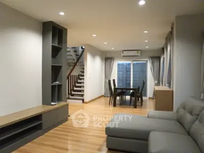 Spacious modern living room with elegant furniture and dining area, featuring sleek wooden flooring and stylish decor.