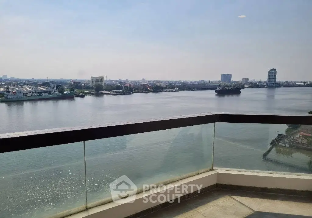 Stunning waterfront view from a high-rise balcony with glass railing, perfect for serene living.