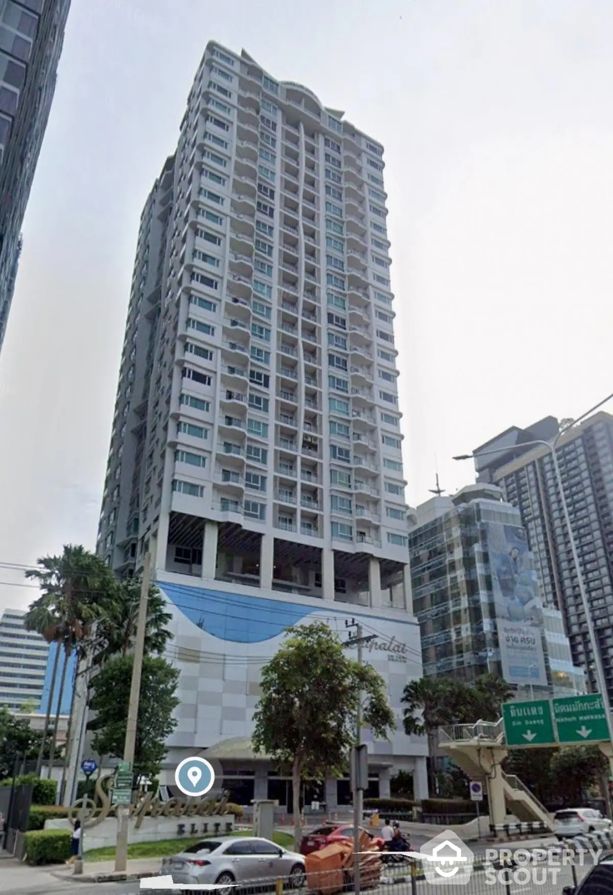 Modern high-rise condominium building in urban setting with lush greenery and city views.