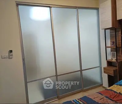 Modern bedroom with frosted glass sliding doors and stylish wooden shelving.
