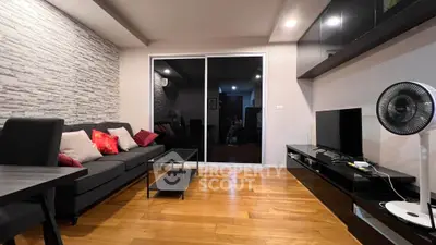 Modern living room with sleek furniture and wooden flooring, featuring a stylish entertainment unit and cozy seating.