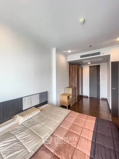 Spacious modern bedroom with stylish wooden furniture and cozy bedding in a contemporary apartment.