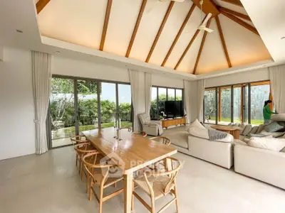 Spacious living room with high ceilings and garden view, featuring elegant wooden dining table and cozy seating area.