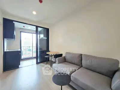 Modern living room with cozy sofa and open kitchen layout, featuring a balcony with natural light.