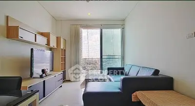 Modern living room with sleek furniture and city view balcony in high-rise apartment.