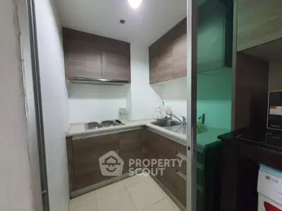 Compact modern kitchen with sleek wooden cabinets and built-in appliances in a cozy apartment.