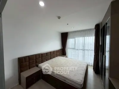 Spacious bedroom with large window and modern furnishings in a stylish apartment.