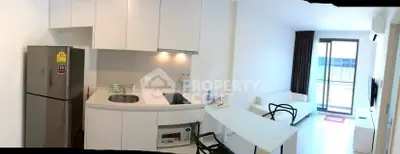 Modern compact kitchen and living area with balcony access in a bright apartment.