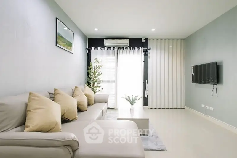 Modern living room with sleek design and neutral tones, featuring a comfortable sofa and wall-mounted TV.