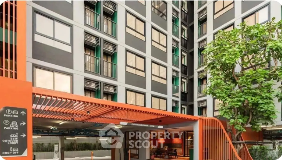 Modern apartment building entrance with parking and drop-off area, featuring contemporary design and lush greenery.