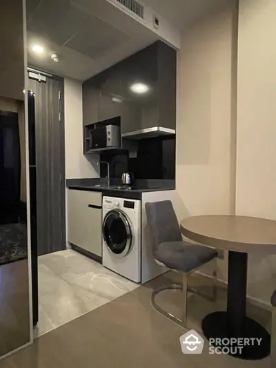 Modern compact kitchen with washing machine and dining area in stylish apartment