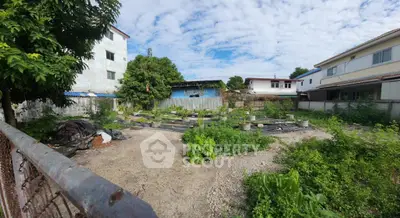 Spacious vacant lot with potential for development in a residential area, surrounded by greenery and neighboring houses.