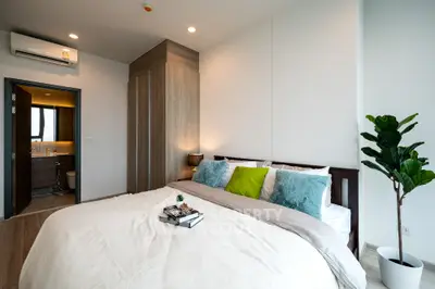 Modern bedroom with cozy decor and ensuite bathroom in luxury apartment.