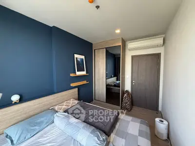 Modern bedroom with blue accent wall, mirrored wardrobe, and air conditioning unit.