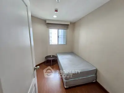 Cozy minimalist bedroom with single bed and window view, perfect for urban living.