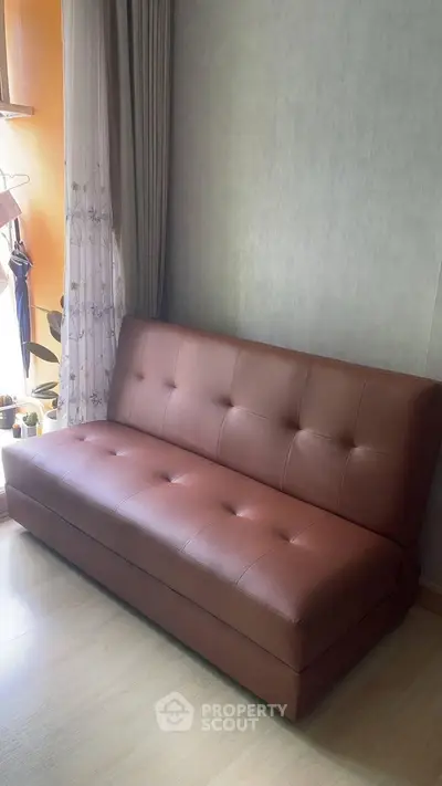 Cozy living room with stylish brown leather sofa and elegant curtains.