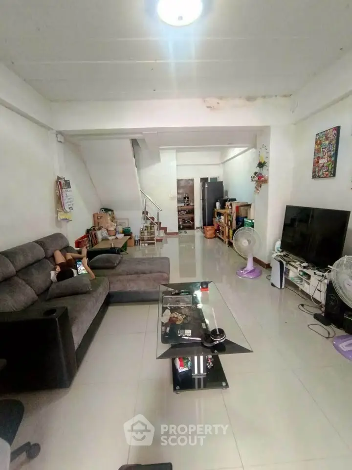Spacious living room with modern furniture and sleek tile flooring, perfect for family gatherings.
