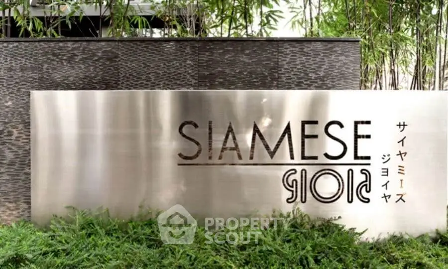 Elegant entrance sign of Siamese Gioia amidst lush greenery, showcasing modern architectural design.