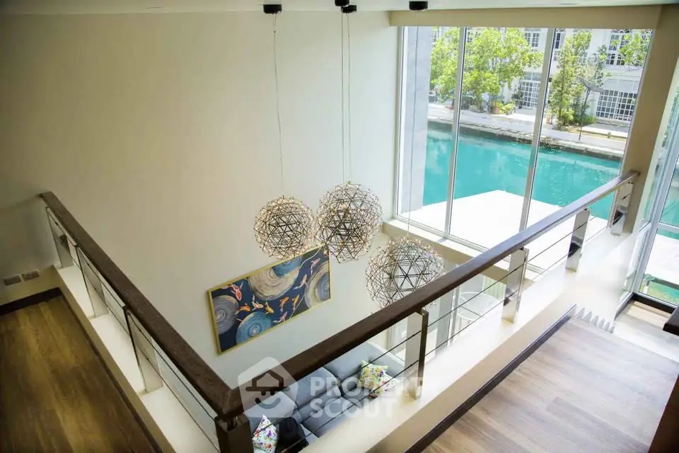 Stunning modern living room with high ceilings and canal view, featuring elegant lighting and artwork.