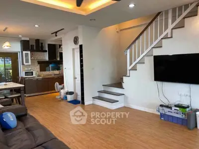 Spacious living room with modern kitchen and staircase, perfect for family gatherings.