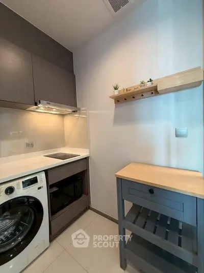 Modern kitchen with sleek appliances and minimalist design, featuring a washing machine and ample storage space.