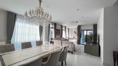 Luxurious open-plan living and dining area with elegant chandelier and modern furnishings.