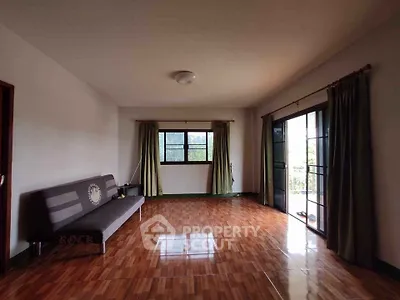 Spacious living room with large windows and wooden flooring, perfect for natural light.