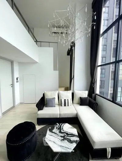 Luxurious modern living room with high ceilings, elegant chandelier, and stylish furniture in a bright apartment.