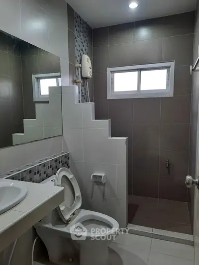 Modern bathroom with sleek tiles and shower area in a contemporary home.