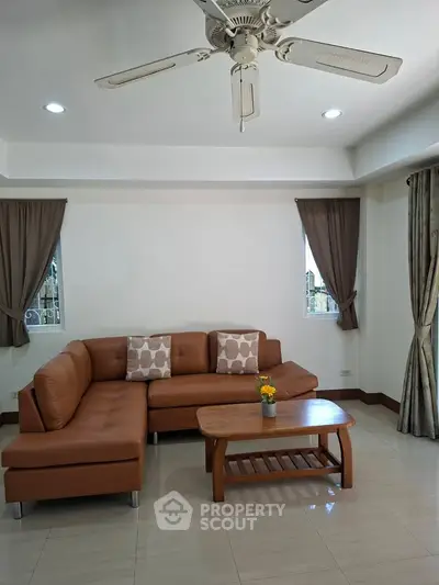 Spacious living room with brown leather sofa and wooden coffee table, perfect for relaxation.