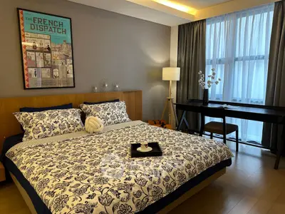 Elegant bedroom with stylish decor and natural light, featuring a cozy bed and a work desk by the window.