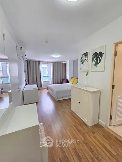 Modern bedroom with wooden flooring and stylish decor in a bright apartment.