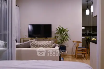 Modern living room with cozy sofa, TV, and stylish kitchen area