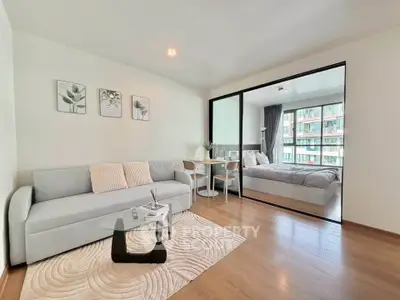 Modern living room with cozy sofa and dining area, adjacent to a bright bedroom with large windows.