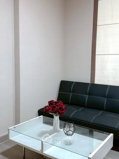 Modern living room with sleek black sofa and elegant glass coffee table.