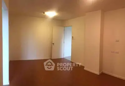 Spacious empty room with wooden flooring and white walls, ideal for customization.