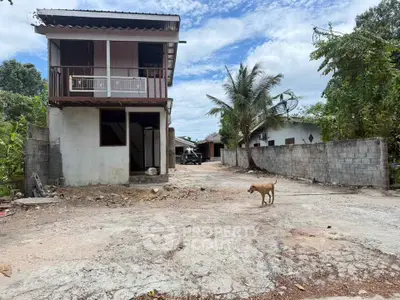 Rustic two-story house with spacious yard and tropical surroundings, ideal for renovation or development.
