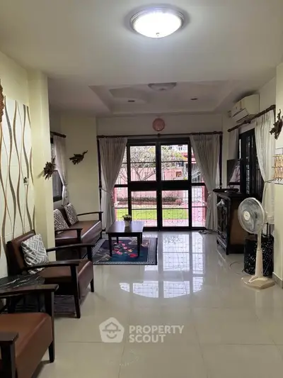 Spacious living room with elegant decor and garden view, perfect for family gatherings.