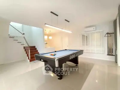 Spacious modern living area with pool table and elegant staircase, perfect for entertainment and relaxation.