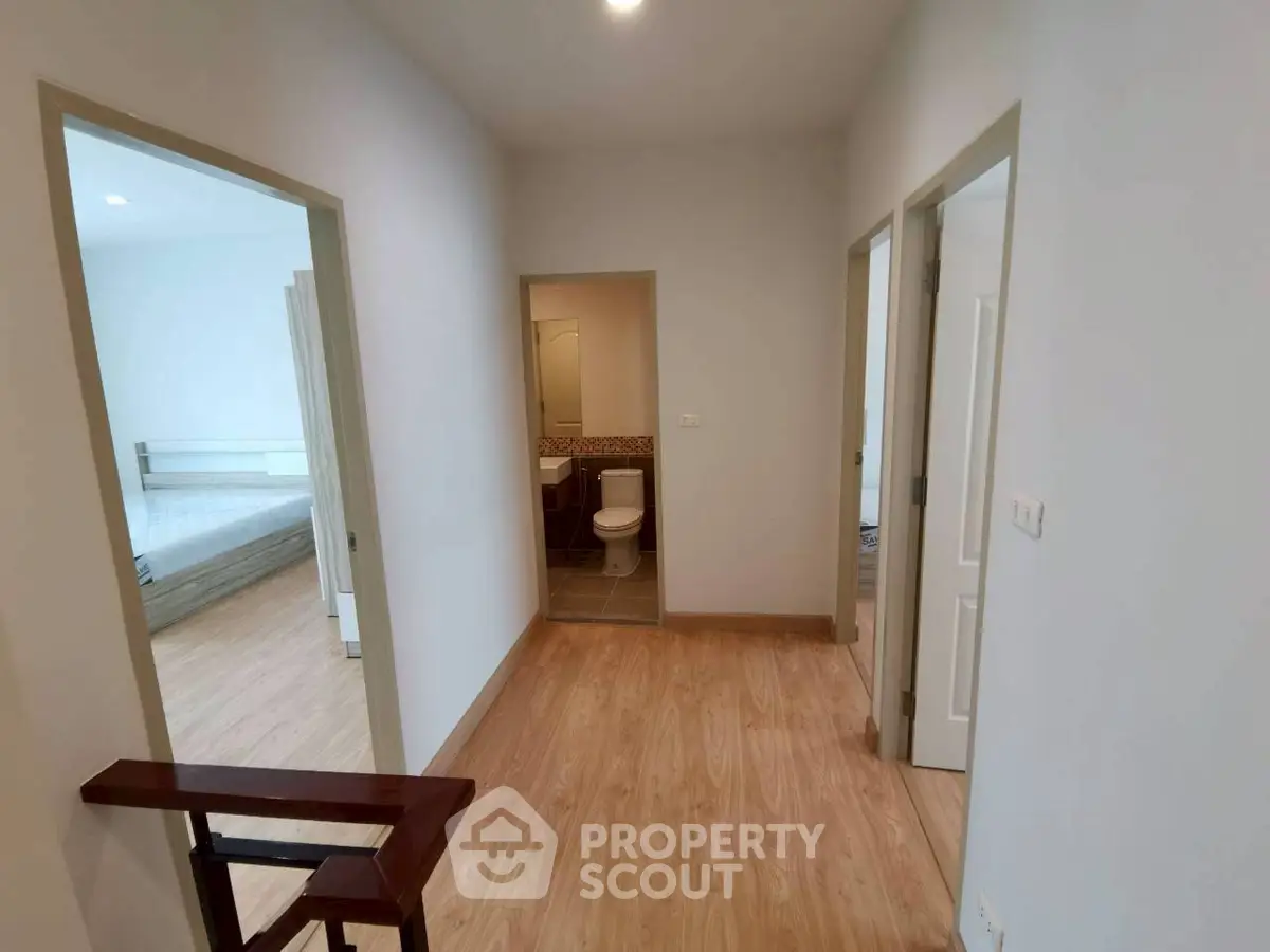 Spacious hallway leading to bedrooms and bathroom in modern apartment.