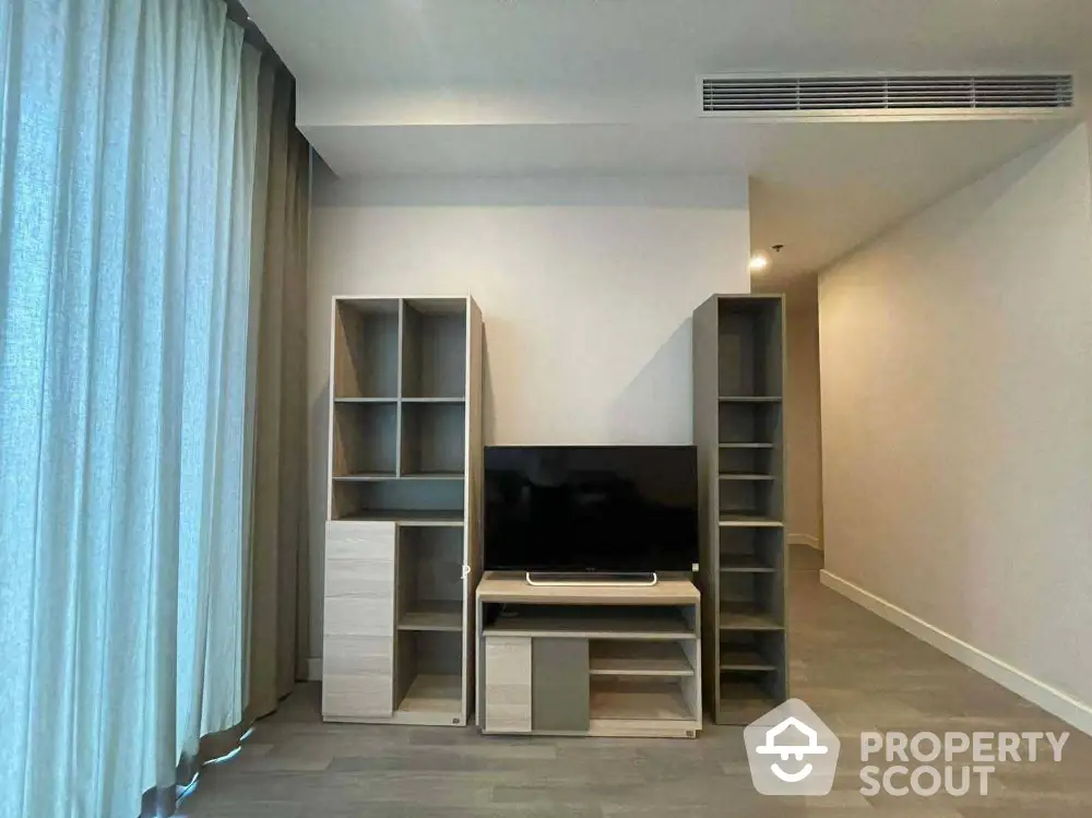 Modern living room with sleek TV stand and shelving units, featuring elegant curtains and minimalist design.