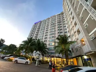 Modern high-rise residential building with palm trees and parking area at dusk.